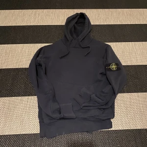 Stone island hoodie - Stone Island hoodie i storlek M. Bra skick förutom ett litet ”hål” på ryggen som knappt syns (bild 3). Har även gått upp ett litet hål vid fickan (skriv för bild). Köpt på stone island affären i stockholm. Pris kan diskuteras vid snabb affär.