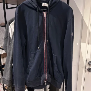 Moncler Zip Up Hoodie - Moncler Zip Up Hoodie i utmärkt skick, lite trög zipper annars perfekt. Går fortfarande bra att stänga bara lite trög. Storlek XL fits M/L, nypris 5500kr mitt pris 1800. Bara att skriva vid frågor eller funderingar! Över 50 refs finns :)