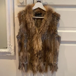 Pälsväst - Äkta pälsväst gjort på kaninpäls och är en rest produkt från livsmedelsproduktion, samt på tvättbjörns päls.    Storlek M.  Pris kan diskuteras! :)