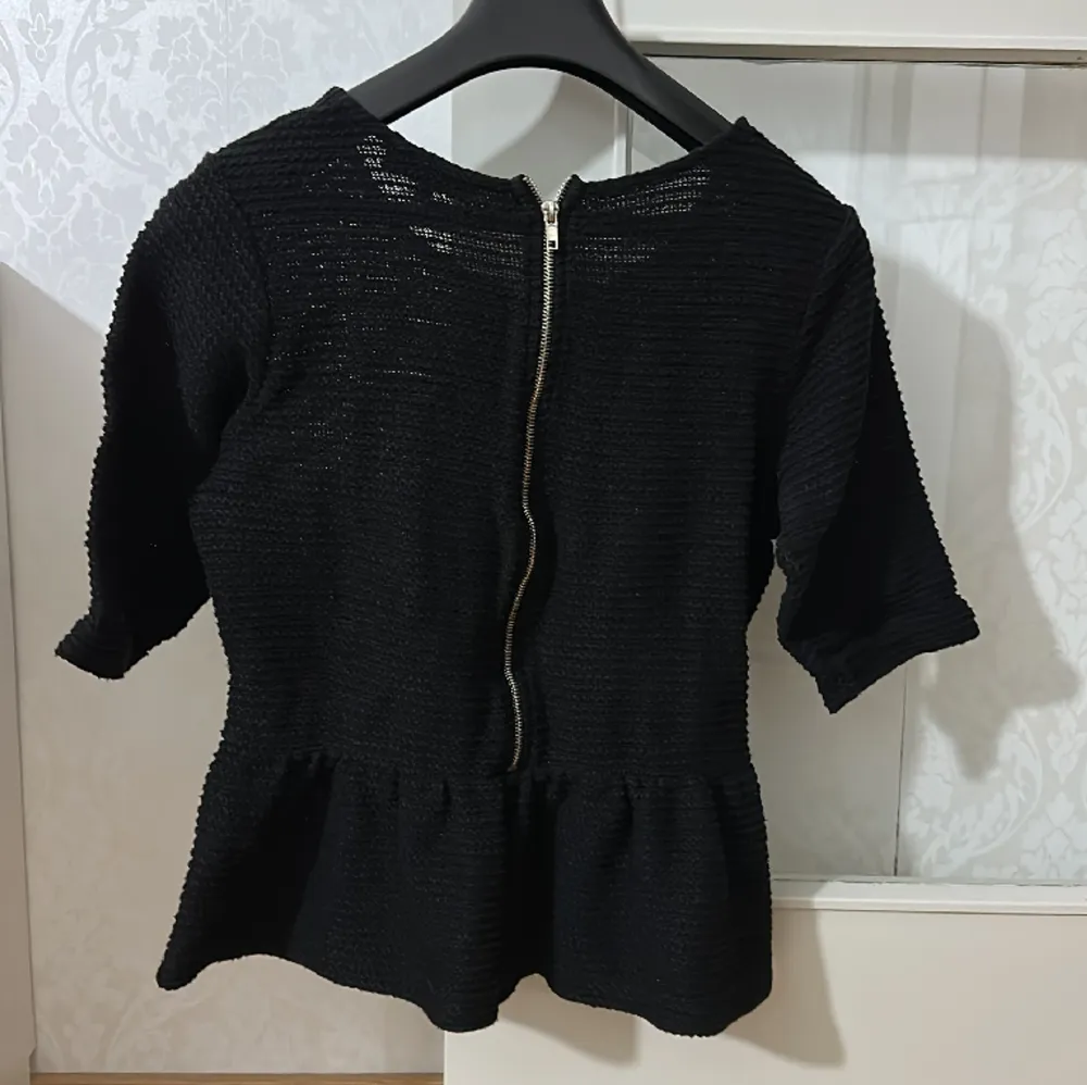 Svart tröja med volang ner till storlek L och köpt från Bikbok . Neuletakit & Villapaidat.