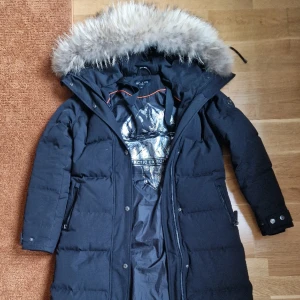 Hollies metro lång vinter dunjacka - Säljer min vinterjacka från märket Hollies i deras modell Metro. Det är Hollies varmaste jacka. Knappt använd en säsong kunde inte användas denna då den blivit för liten. Nyskick på jackan. Jag är 170 cm lång. Nypris 6869 kr