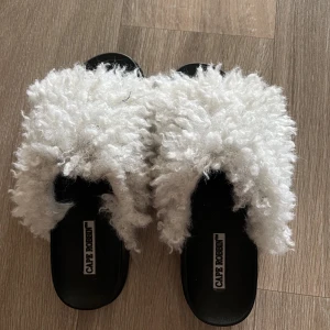 tofflor  - svarta tofflor med vit päls från chiquelle. använd en del men fortfarande i fint skick. Står storlek 7