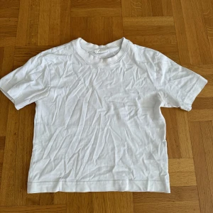 T-shirt - Vit t-shirt i kortare modell från Gina. (Frakt tillkommer) 