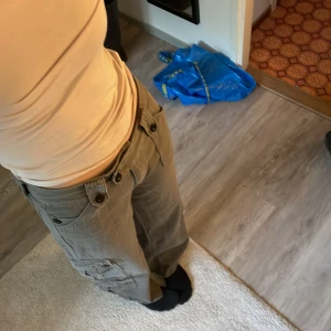 Grå gröna cargobyxor y2k - Snygga lågmidjade cargobyxor med en blandad färg av grå och grön. Y2k.  Bra fickor och bra knappar. Blixtlås och knappar vid gylfen. Hållbart material