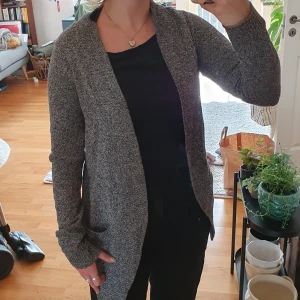 Kofta - Stickad tunn kofta i grå/svart/vitt med fickor och ribbad kant.