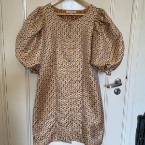 Orange mönstrad klänning - Fin orange mönstrad klänning med stora puffärmar från A-View, storlek 38🧡Endast använd en gång (på sista bilden, obs korsetten ingår ej) säljes då den är för stor för mig. 