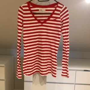 Långärmad tröja  - En röd och vit randig långärmad tröja, men loga på bröstet.