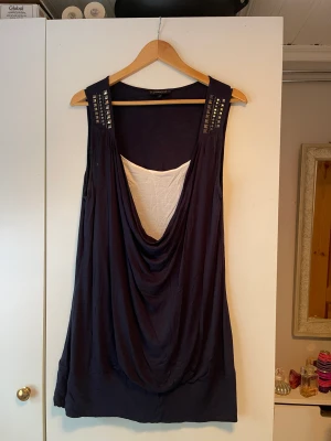 Blus - En blus med paljetter på axlarna, vit och mörkblå. 