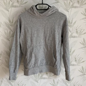Hoodi - En grå hoodi med luva och mag ficka. 