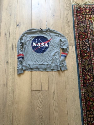Tunn sweatshirt  - En grå Nasa sweatshirt från Hm i storlek S. Använd lite grann men inte speciellt mycket. I gott skick, säljer för att den är för liten för mig. Nypris 200 kr. Skön att ha nu till hösten, köparen står för frakten 😊
