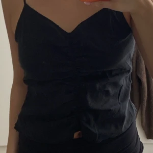 Svart linne med dragkedja  - Aldrig använt! Har en dragkedja på sidan och man kan justera bandens längd.  Strl 42 men skulle mer säga en M.