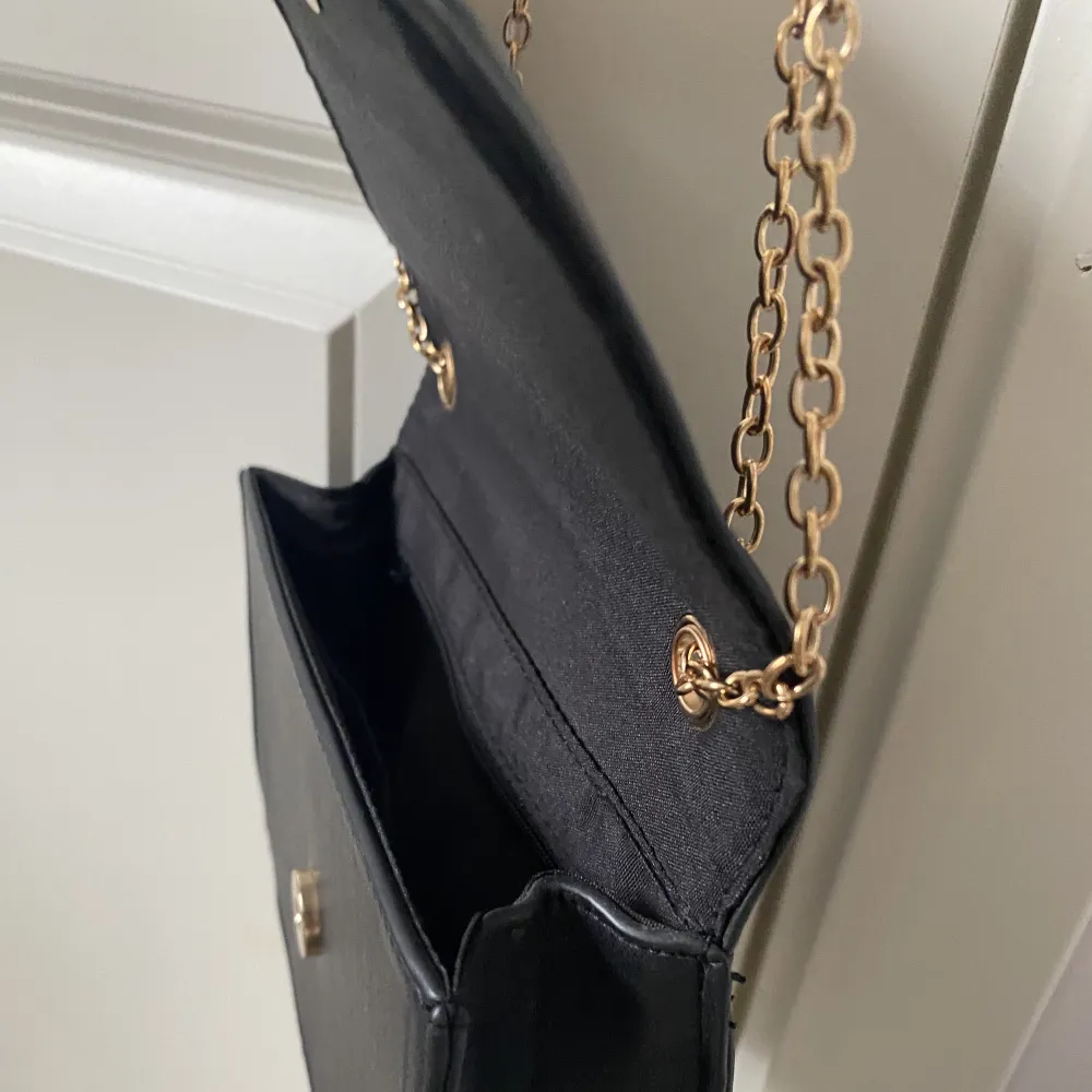 En svart stilren väska med gulddetaljer. Kan användas på lite olika sätt. Använd ett fåtal gånger, i mycket bra skick.✨. Väskor.