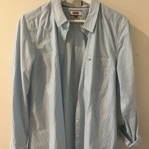 Skjorta Tommy Jeans - Blåvitrandig skjorta från Tommy Jeans. Figursydd. Upplever den något liten i storleken, så passar även M. Aldrig använd 