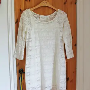 En jättefin vit klänning med spetstyg och silkeslen innerklänning. Passar perfekt under sommaren eller till studenten och skolavslutningar.   Märke: H&M Storlek: 38