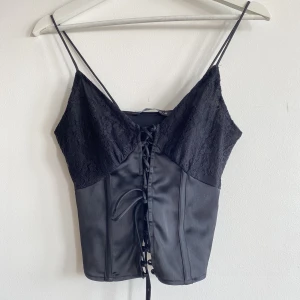 Korsettopp  - Topp i korsettstil med knytdetalj fram. Aldrig använd, säljes pga för liten. Sjukt snygg, lite 00-tals vibe.