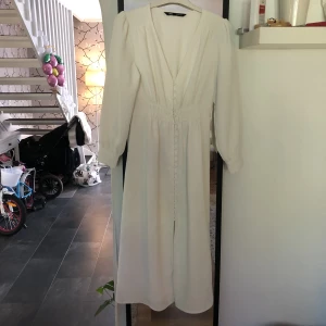 Vit långklänning från Zara - Som ny. Vit lång klänning från Zara med knappar hela vägen. Strl Small. Perfekt för student eller skolavslutningen eller bara en vanlig sommardag.