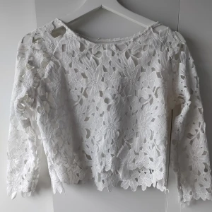 Vit blommig blus - En vit blommig blus med lite ungefär 3/4s armar.  Passar en Xs. 