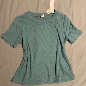 En grön/blå top från lindex, från barnavdelningen. Den passar mig som har XS/S på tröjor. Eftersom den är för barn så kan den vara tajt i ärmarna. Prislapp är kvar. 