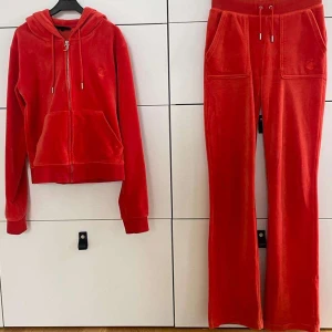 Juicy Couture set - Juicy Couture set i orange-röd färg. I bra skick, dock någon fläck nere vid ankeln på byxorna. Säljes pågrund av att de inte passar mig längre.  Inga byten mot andra set och man kan köpa separat, skriv isånnafall 