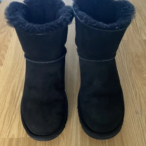 Svarta UGG’s - Svarta UGG stl. 37 med svart siden rosett baktill