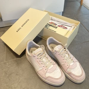 Arigatos Rosa  - Damskor i storleken 40 av märket Axel Arigato. Kvalitativa skor som har tydliga tecken på användning. Kvitto, låda och bag medföljer.  Inga hål, kosmetiska skador eller dylikt. Skick 7/10 Strlk: 40