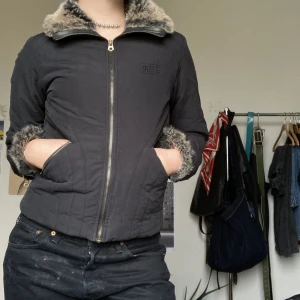 2000tals dunjacka  - En relativt slim fit jacka med syntestisk päls på kragen och vid ärmarna. Den har detaljer av sömnad längs med sidorna, inga skador - gott skick, pris kan diskuteras 