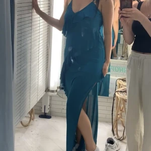 Långklänning - Grönblå långklänning från Bershka. Skiftar i nyans beroende på ljus. Prislappen sitter kvar då jag inte haft tillfälle att använda klänningen.  Nypris 399 mitt pris 200