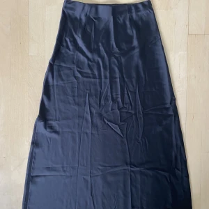 Långkjol  - Svart långkjol i satin från bikbok. Kjolen har resor i midjan och en kort slits längst ned. Kjolen är väl omhändertagen och i mycket bra skick.