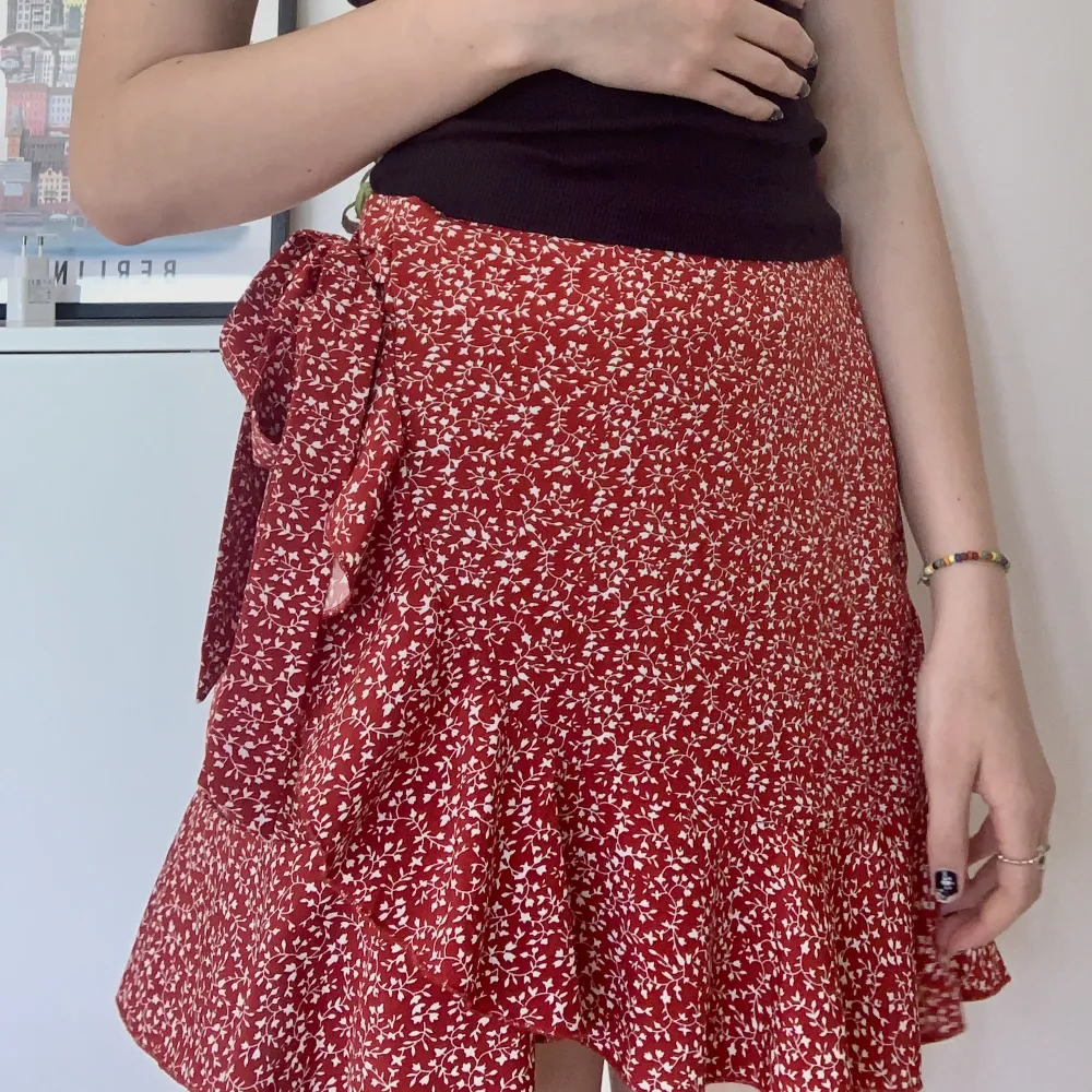 Jättefin röd kjol med vita detaljer på ❤️ endast testad, säljer pga att den aldrig kommer till användning. Väldigt härligt tyg med blixtlås i sidan och knytning, perfekt nu till sommaren 🫶🏻☀️. Kjolar.