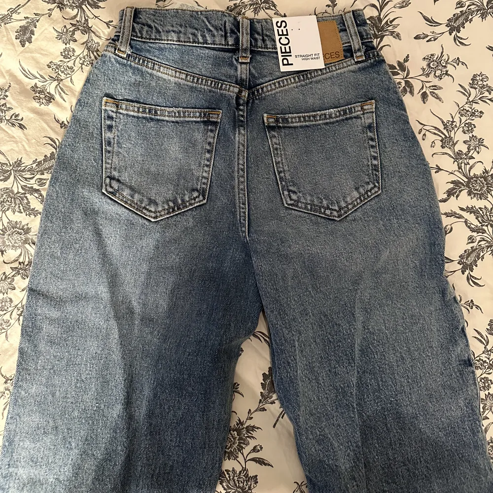 Helt nya jeans från Pieces. Har en slits vid bensluten. Storlek 26/32. Passar bra på mig som vanligtvis bär storlek Xs.. Jeans & Byxor.