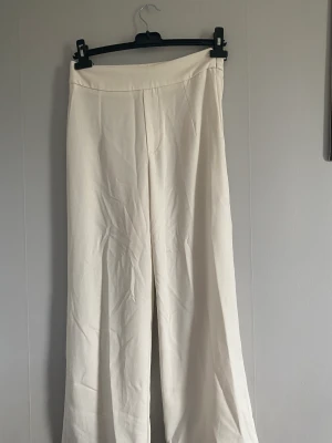 Vita kostymbyxor - Vita kostymbyxor med högmidja från Bikbok, storlek S, 36. De är uppsydda och jag är 153 cm lång! Använda 1 gång. Lite genomskinliga!