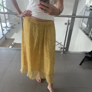 Gul lowwaist/highwaist sommarkjol - Fin och flowig kjol perfekt för varma sommardagar. Går utmärkt att använda både som lowwaist och/eller highwaist - elastisk midja. Elastiska bandet kan upplevas lite konstigt men den rätar ut sig när man tar på sig kjolen! Normal i storleken.