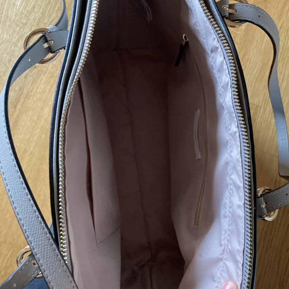 En rymlig grå handväska från H&M. Helt oanvänd🌸Den är 15 cm bred, 40cm lång och 30cm hög. Den har några små vita fläckar på handtagen som man inte ser så mycket och lite mörka sträck på sidorna som ni ser på sista bilderna💐. Väskor.