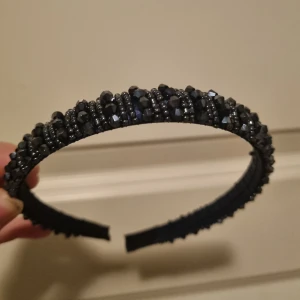 Mörkblått diadem  - Ett mörkblått diadem med pärlor. Passar på flera då det går att böja. Ingår i blåa balklänningen. Använt en gång, i bra skick. 