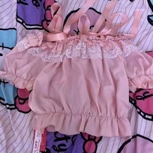 Rosa fin topp med vita saker på - Säljer för att den inte kommer till användning, fint skick och har inga fläckar på sig! Använt Max 1 gång vid testning! Bandet vid axlarna går att ändra på.  Klicka på köp om du vill köpa, kontakta om du har frågor!