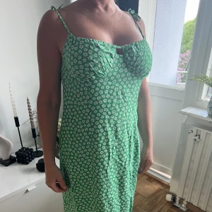 grön klänning  - grön klänning med blom-detaljer från H&M. Endast testad aldrig använd :) Har några skrynkliga märken på klänningen men jag stryker den innan frakt!