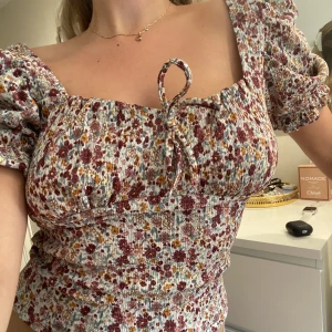 Söt blommig topp  - Sååå söt topp Från Gina strl S. Helt perfekt till sommaren, säljer pga inte kommer till användning längre. Lite puff ärmar och liten rosett vid bysten🌸💞