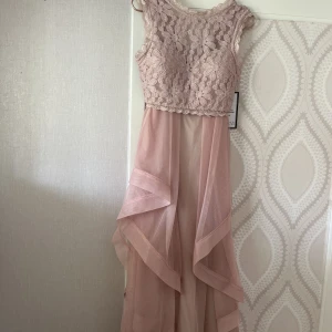Helt oanvänd tvådelad balklänning med taggar!! Rosa/beige - Säljer nu otroligt fin klänning köpt på Macy’s i New york!!! HELT NY ALDRIG ANVÄND!. Färgen är i Dusty rose (rosa/beige) och tvådelad, kjolen och toppen sätts på separat. Perfekt till bal eller finare evenemang! 
