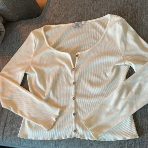 En krämvitfärgad tröja med knappar - En krämvitfärgad tröja med knappar från NA-KD från märket PAMELA i storlek M.  Jättefin skön tröja, stretchig, bra längd, inte för tjock, inte för tunn. Funkar till ett par jeans, även till kjol. 🌸