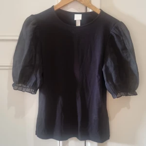 Topp med puffärm - Svart topp från hm. Oanvänd med lapp kvar. Ärmarna är genomskinliga med glitter