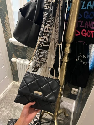Handväska  - En svart handväksa som har guld ditaljer. Perfekt storlek enligt mig får plats med mycket 💕