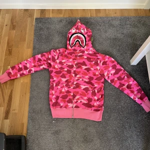 Bape hoodie rosa - Bra bape hoodie i jätte bra skick, skriv om det är några frågor. Storlek M passar som en L, inte äkta tyväär pris kan diskuteras vid snabb affär