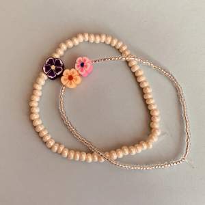 2 blommiga armband, en vit med en lila blomma, en silver med en rosa och orange blomma! 50kr som par + 15kr (sänkt från 45kr styck 05/03/2024)