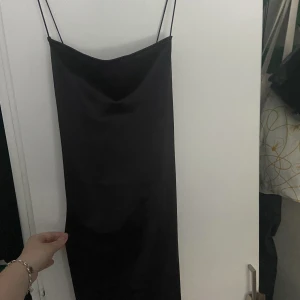 Svart kort satinklänning  - Helt oanvänd satinklänning, jättefin men kommer ej till användning. Inte exakt den på bilden men väldigt lik. Lite tajtare bara, iaf på mig :) Kors i ryggen. Det är storlek XL men skulle mer säga L