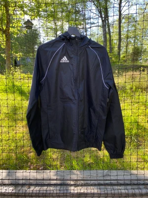 Adidas regnjacka - En regnjacka från Adidas med luva i storlek XS. Mycket fint skick.