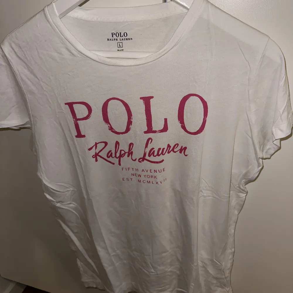 Vit tisha från Ralph Lauren med märkesnamnet tryckt i rosa. True to size! Fint skick. T-shirts.