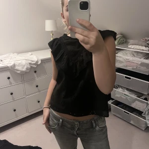 Svart blus  - En super söt blus med volang och små Blom detaljer. Den är aldrig använd  Liten i storleken