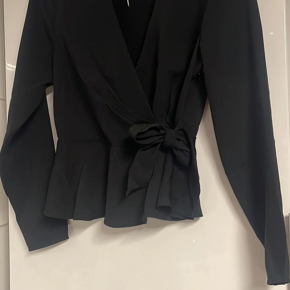 Svart blus med rosett från Nelly, som aldrig blivit använd. :) strl 36. Puserot.