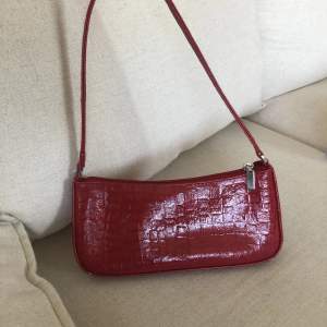 Jättesöt röd handväska med snygg detalj på baksidan. Har ett innerfack också. 