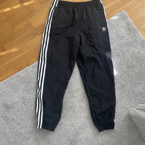 Adidasbyxor - Vindbyxor från adidas. De är i nyskick och använda någon enstaka gång! Snören i midjan som kan anpassas